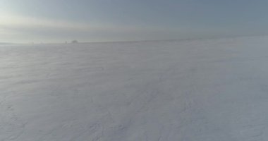 Soğuk kış kutup bölgesinin insansız hava görüntüsü, ufukta karla kaplı ağaçlar, buz nehri ve güneş ışınları. Aşırı düşük sıcaklık havası.