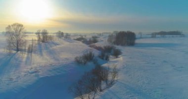 Soğuk kış kutup bölgesinin insansız hava görüntüsü, ufukta karla kaplı ağaçlar, buz nehri ve güneş ışınları. Aşırı düşük sıcaklık havası.