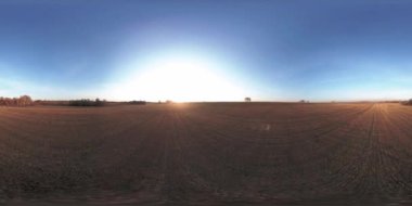 360 hava manzaralı. Güneşli bir sonbahar akşamında sonsuz yeşil tarlaları olan yaz manzarasının üzerinde alçak uçuş. Ufuktaki güneş ışınları. Hızlı yatay hareket. Tarım arazisi insansız hava aracı atışı. Dengeli