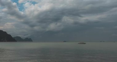 Kumsalda ve teknelerle deniz manzarasında yağmur bulutları hızlanıyor. Rüzgarlı hava ve dramatik gökyüzü. Okyanusta tropik fırtına.