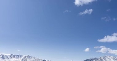 Güneş hareketinin 4K UHD zaman dilimi kristal berrak gökyüzünde ve karlı dağın tepesinde bulutlar. Sonbahar yüksek rakımlı çayırlarda sarı çimenler. Uçsuz bucaksız. Kamera hareketi
