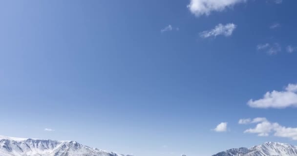 4K超高清太阳在晶莹的天空中移动的时间 雪山顶上布满了云彩 秋天的高原地区黄草丛生 野生无尽的天性 照相机运动 — 图库视频影像