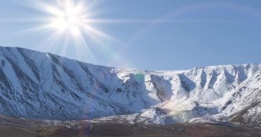 Güneş hareketinin 4K UHD zaman çizelgesi karlı dağın tepesinde kristal berrak gökyüzünde. Sonbahar otlağında sarı çimenler. Vahşi sonsuz doğa..