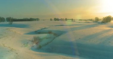 Soğuk kış kutup bölgesinin insansız hava görüntüsü, ufukta karla kaplı ağaçlar, buz nehri ve güneş ışınları. Aşırı düşük sıcaklık havası. Sibirya