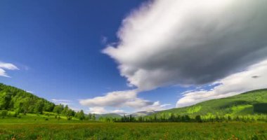 Yaz ya da sonbahar mevsiminde dağdaki çayır zaman atlaması. Vahşi doğa ve kırsal alan. Bulutların hareketi, yeşil çimenler ve güneş ışınları. Motorlu Panorama