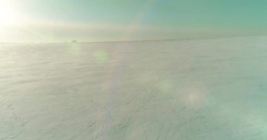 Soğuk kış kutup bölgesinin insansız hava görüntüsü, ufukta karla kaplı ağaçlar, buz nehri ve güneş ışınları. Aşırı düşük sıcaklık havası.