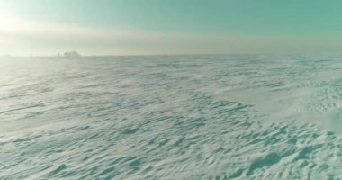 Soğuk kış kutup bölgesinin insansız hava görüntüsü, ufukta karla kaplı ağaçlar, buz nehri ve güneş ışınları. Aşırı düşük sıcaklık havası.