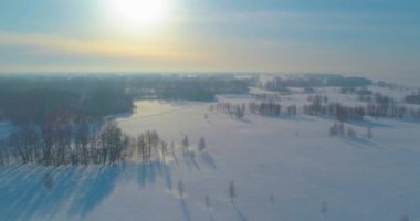 Soğuk kış kutup bölgesinin insansız hava görüntüsü, ufukta karla kaplı ağaçlar, buz nehri ve güneş ışınları. Aşırı düşük sıcaklık havası.