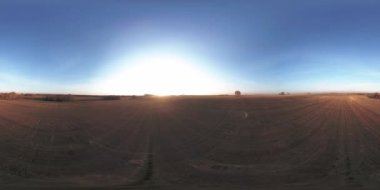 360 hava manzaralı. Güneşli bir sonbahar akşamında sonsuz yeşil tarlaları olan yaz manzarasının üzerinde alçak uçuş. Ufuktaki güneş ışınları. Hızlı yatay hareket. Tarım arazisi insansız hava aracı atışı. Dengeli