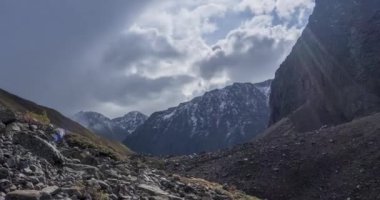 Yaz ya da sonbahar zamanı Dağ Vadisi 'ndeki destansı bulutların 4k UHD zaman çizelgesi. Vahşi sonsuz doğa ve kar fırtınası gökyüzü. Kar zirvesinde güneş ışınları. Hızlı hareket