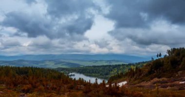 Dağ Gölü yaz ya da sonbahar zamanında zaman atlaması. Vahşi doğa ve kırsal alan. Hızlı bulutlar, yeşil çimenler ve dramatik gökyüzü. Motorlu doli kaydırma hareketi