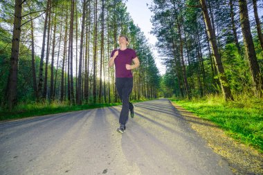 Koşan adam güzel bir yaz gününde şehir parkında koşuyor. Spor fitness modeli Kafkasya etnik köken eğitimi.