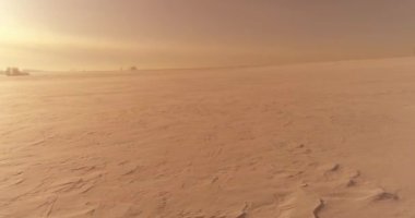 Soğuk kış kutup bölgesinin insansız hava görüntüsü, ufukta karla kaplı ağaçlar, buz nehri ve güneş ışınları. Aşırı düşük sıcaklık havası.