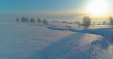 Soğuk kış kutup bölgesinin insansız hava görüntüsü, ufukta karla kaplı ağaçlar, buz nehri ve güneş ışınları. Aşırı düşük sıcaklık havası.