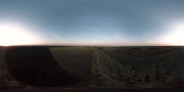 360 hava manzaralı. Güneşli bir sonbahar akşamında sonsuz yeşil tarlaları olan yaz manzarasının üzerinde alçak uçuş. Ufuktaki güneş ışınları. Hızlı yatay hareket. Tarım arazisi insansız hava aracı atışı. Dengeli