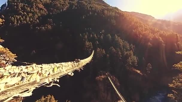 昆布谷地最大的悬索桥 挂满了五彩缤纷的西藏祈祷旗 野生喜马拉雅山高海拔自然和高山山谷 岩石斜坡上覆盖着树木 远足地区至基地营 — 图库视频影像