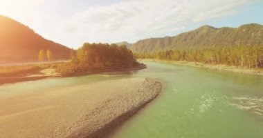 4k UHD hava görüntüsü. Bulutlu yaz sabahında taze soğuk dağ nehri üzerinde alçak uçuş. Horisont 'ta yeşil ağaçlar ve güneş ışınları. Hızlı yatay hareket