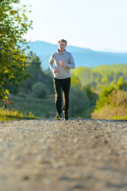Koşan adam güzel bir yaz gününde kırsal alanda koşuyor. Spor fitness modeli Kafkasya etnik köken eğitimi.