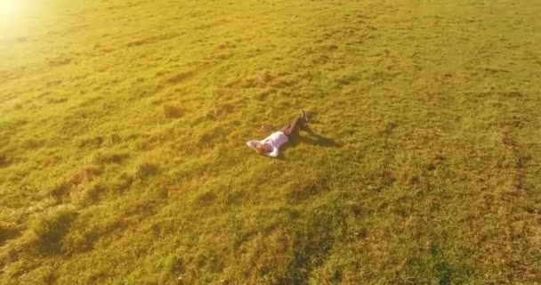 空中展望台 人間の周りの低軌道飛行は 黄色の田園地帯にノートパッドを持つ緑の芝生に横たわっていました 普段着だ 太陽光線 放射線運動 — ストック動画