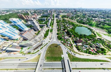 Kesişen yollar, evler, binalar, parklar, otoparklar, köprüler olan havacılık şehri manzarası. Helikopter insansız hava aracı atışı. Geniş Panoramik resim.