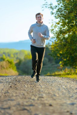 Koşan adam güzel bir yaz gününde kırsal alanda koşuyor. Spor fitness modeli Kafkasya etnik köken eğitimi.