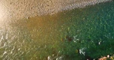 4K hava bakış açısı. Güneşli yaz sabahında, taze, hızlı dağ nehri üzerinde kayalıklarla alçak irtifa uçuşu. Yeşil çam ağaçları ve güneş ışınları. Saf soğuk su akıntısı.