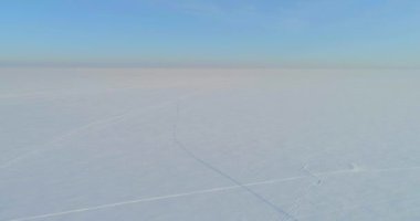 Soğuk kış kutup bölgesinin insansız hava görüntüsü, ufukta karla kaplı ağaçlar, buz nehri ve güneş ışınları. Aşırı düşük sıcaklık havası.
