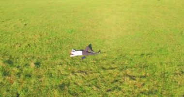 Havadan bakış açısı. Sarı kırsal alanda yeşil çimlerin üzerinde dizüstü bilgisayarı olan bir adam etrafında alçak yörüngeden uçuyordu. Sıradan giyinmiş. Güneş ışınları. Radikal hareket.
