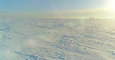 Soğuk kış kutup bölgesinin insansız hava görüntüsü, ufukta karla kaplı ağaçlar, buz nehri ve güneş ışınları. Aşırı düşük sıcaklık havası.