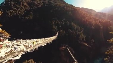 Khumbu vadisindeki en büyük asma köprü renkli Tibet dua bayraklarıyla. Vahşi Himalayalar yüksek irtifa doğa ve dağ vadisi. Ağaçlarla kaplı kayalık yamaçlar. Trek alanı ana kampa gidiyor.