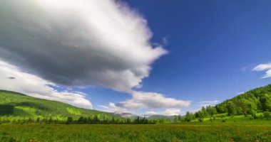 Yaz ya da sonbahar mevsiminde dağdaki çayır zaman atlaması. Vahşi doğa ve kırsal alan. Bulutların hareketi, yeşil çimenler ve güneş ışınları. Motorlu Panorama