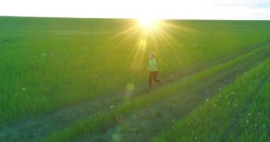 Sportif bir çocuğun havadan çekimleri buğday tarlasından geçiyor. Kırsal çayırlarda akşam sporu alıştırmaları. Mutlu bir çocukluk sağlıklı bir yaşam biçimidir. Açık havada koşma transferi. Radikal hareket, güneş