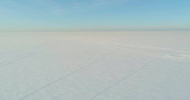 Soğuk kış kutup bölgesinin insansız hava görüntüsü, ufukta karla kaplı ağaçlar, buz nehri ve güneş ışınları. Aşırı düşük sıcaklık havası.