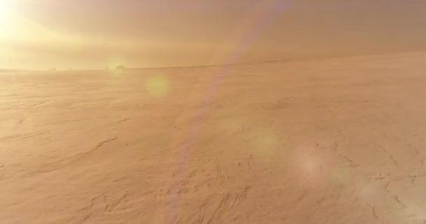 Drone aerial view of cold winter landscape arctic field, trees covered with frost snow, ice river and sun rays over horizon. Extreme low temperature weather.