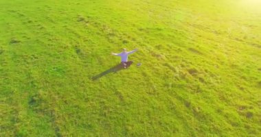 Havadan bakış açısı. Yeşil çimlerde oturan ve kırsal alanda not defteri olan bir adamın etrafında alçak yörünge uçuşları. Gündelik kıyafet ve Zen meditasyonu. Eller havada. Güneş ışınları. Radikal hareket.