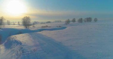 Soğuk kış kutup bölgesinin insansız hava görüntüsü, ufukta karla kaplı ağaçlar, buz nehri ve güneş ışınları. Aşırı düşük sıcaklık havası.
