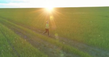 Sportif bir çocuğun havadan çekimleri buğday tarlasından geçiyor. Kırsal çayırlarda akşam sporu alıştırmaları. Mutlu bir çocukluk sağlıklı bir yaşam biçimidir. Açık havada koşma transferi. Radikal hareket, güneş