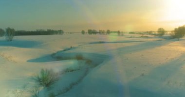 Soğuk kış kutup bölgesinin insansız hava görüntüsü, ufukta karla kaplı ağaçlar, buz nehri ve güneş ışınları. Aşırı düşük sıcaklık havası. Sibirya