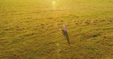 Havadan bakış açısı. Yeşil çimlerde oturan ve kırsal alanda not defteri olan bir adamın etrafında alçak yörünge uçuşları. Gündelik kıyafet ve Zen meditasyonu. Eller havada. Güneş ışınları. Radikal hareket.