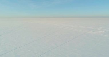 Soğuk kış kutup bölgesinin insansız hava görüntüsü, ufukta karla kaplı ağaçlar, buz nehri ve güneş ışınları. Aşırı düşük sıcaklık havası.