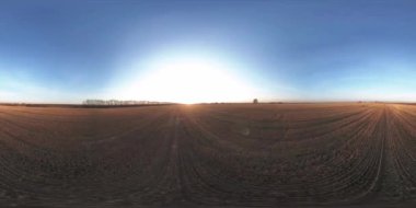 360 hava manzaralı. Güneşli bir sonbahar akşamında sonsuz yeşil tarlaları olan yaz manzarasının üzerinde alçak uçuş. Ufuktaki güneş ışınları. Hızlı yatay hareket. Tarım arazisi insansız hava aracı atışı. Dengeli