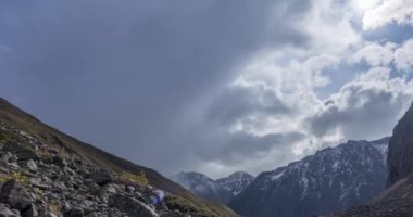 Yaz ya da sonbahar zamanı Dağ Vadisi 'ndeki destansı bulutların 4k UHD zaman çizelgesi. Vahşi sonsuz doğa ve kar fırtınası gökyüzü. Kar zirvesinde güneş ışınları. Hızlı hareket