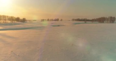 Soğuk kış kutup bölgesinin insansız hava görüntüsü, ufukta karla kaplı ağaçlar, buz nehri ve güneş ışınları. Aşırı düşük sıcaklık havası. Sibirya