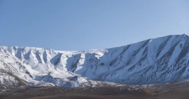 Güneş hareketinin 4K UHD zaman çizelgesi karlı dağın tepesinde kristal berrak gökyüzünde. Sonbahar otlağında sarı çimenler. Vahşi sonsuz doğa..