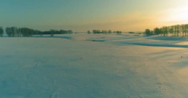Soğuk kış kutup bölgesinin insansız hava görüntüsü, ufukta karla kaplı ağaçlar, buz nehri ve güneş ışınları. Aşırı düşük sıcaklık havası. Sibirya