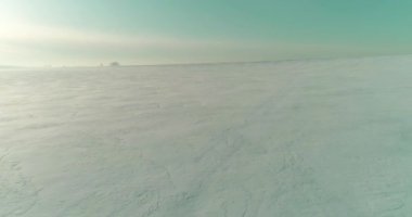 Soğuk kış kutup bölgesinin insansız hava görüntüsü, ufukta karla kaplı ağaçlar, buz nehri ve güneş ışınları. Aşırı düşük sıcaklık havası.