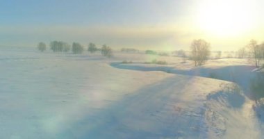 Soğuk kış kutup bölgesinin insansız hava görüntüsü, ufukta karla kaplı ağaçlar, buz nehri ve güneş ışınları. Aşırı düşük sıcaklık havası.