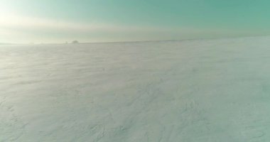 Soğuk kış kutup bölgesinin insansız hava görüntüsü, ufukta karla kaplı ağaçlar, buz nehri ve güneş ışınları. Aşırı düşük sıcaklık havası.