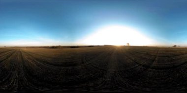 360 hava manzaralı. Güneşli bir sonbahar akşamında sonsuz yeşil tarlaları olan yaz manzarasının üzerinde alçak uçuş. Ufuktaki güneş ışınları. Hızlı yatay hareket. Tarım arazisi insansız hava aracı atışı. Dengeli