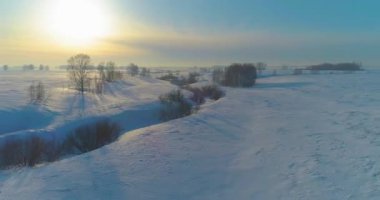 Soğuk kış kutup bölgesinin insansız hava görüntüsü, ufukta karla kaplı ağaçlar, buz nehri ve güneş ışınları. Aşırı düşük sıcaklık havası.